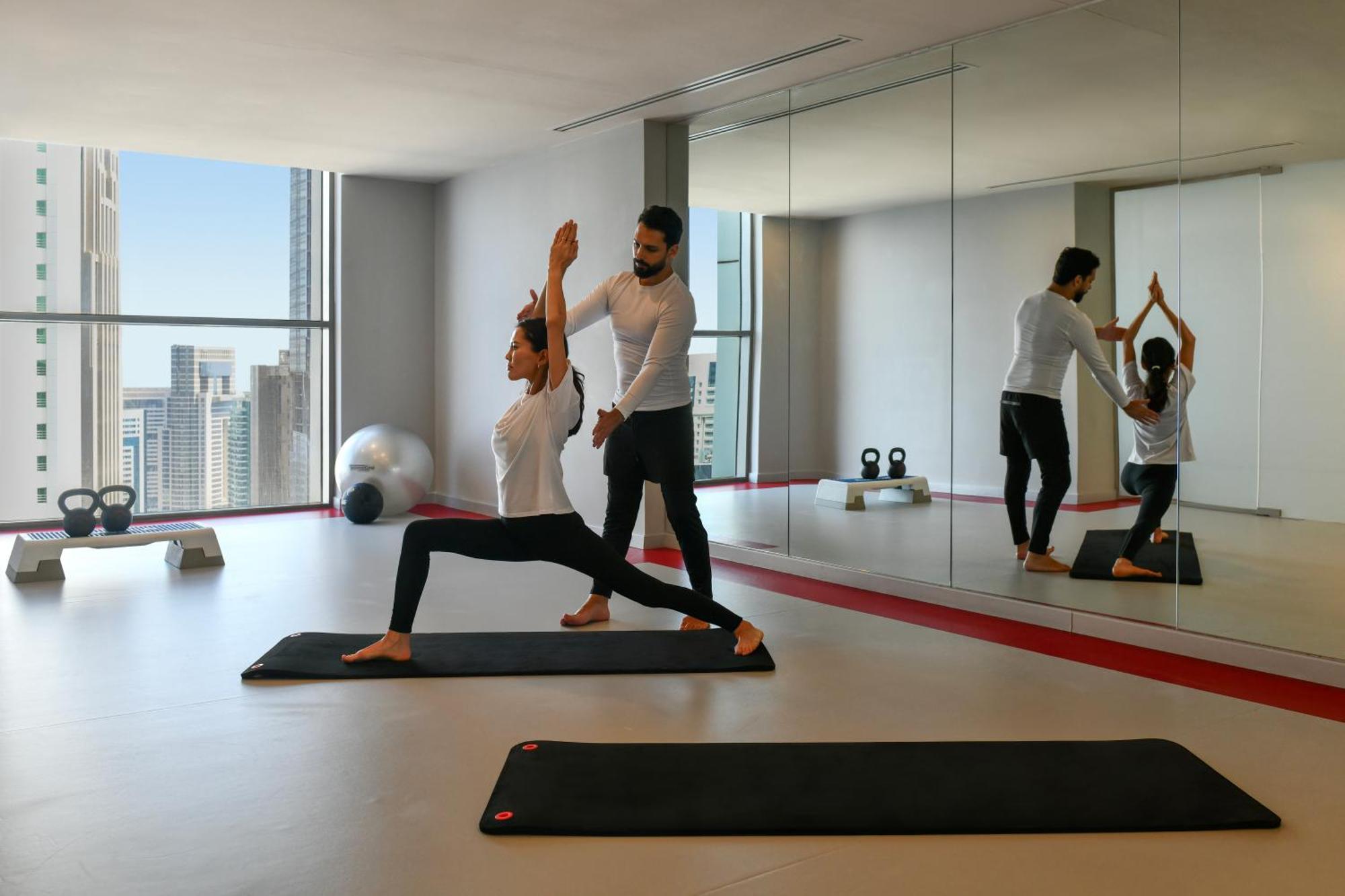 โรงแรมดุสิต โดฮา ภายนอก รูปภาพ A personal trainer assisting a woman with a yoga workout